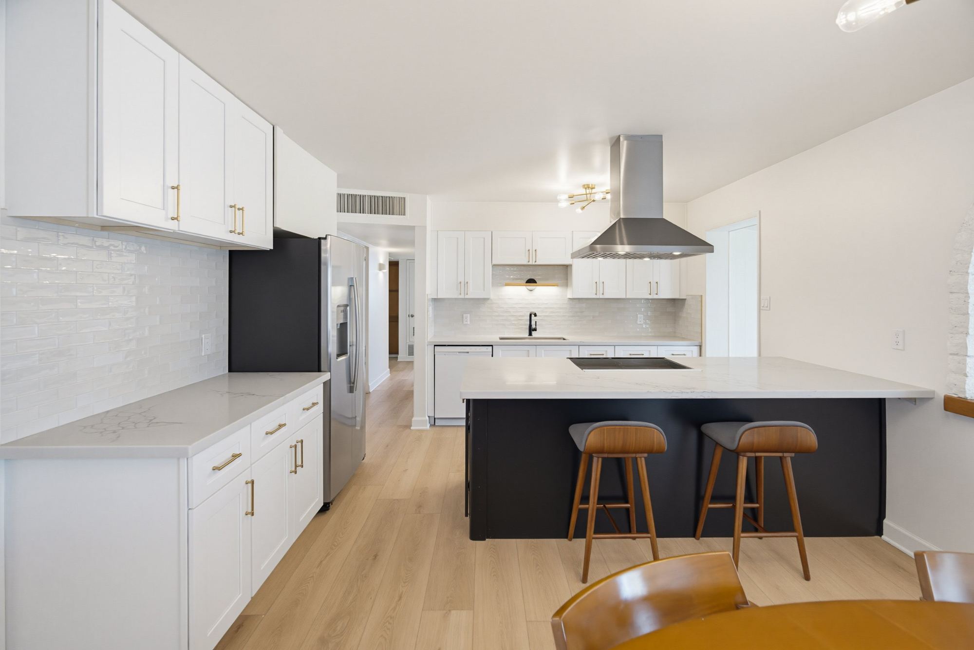 Remodeled kitchen with white shaker cabinets, black island and brass hardware