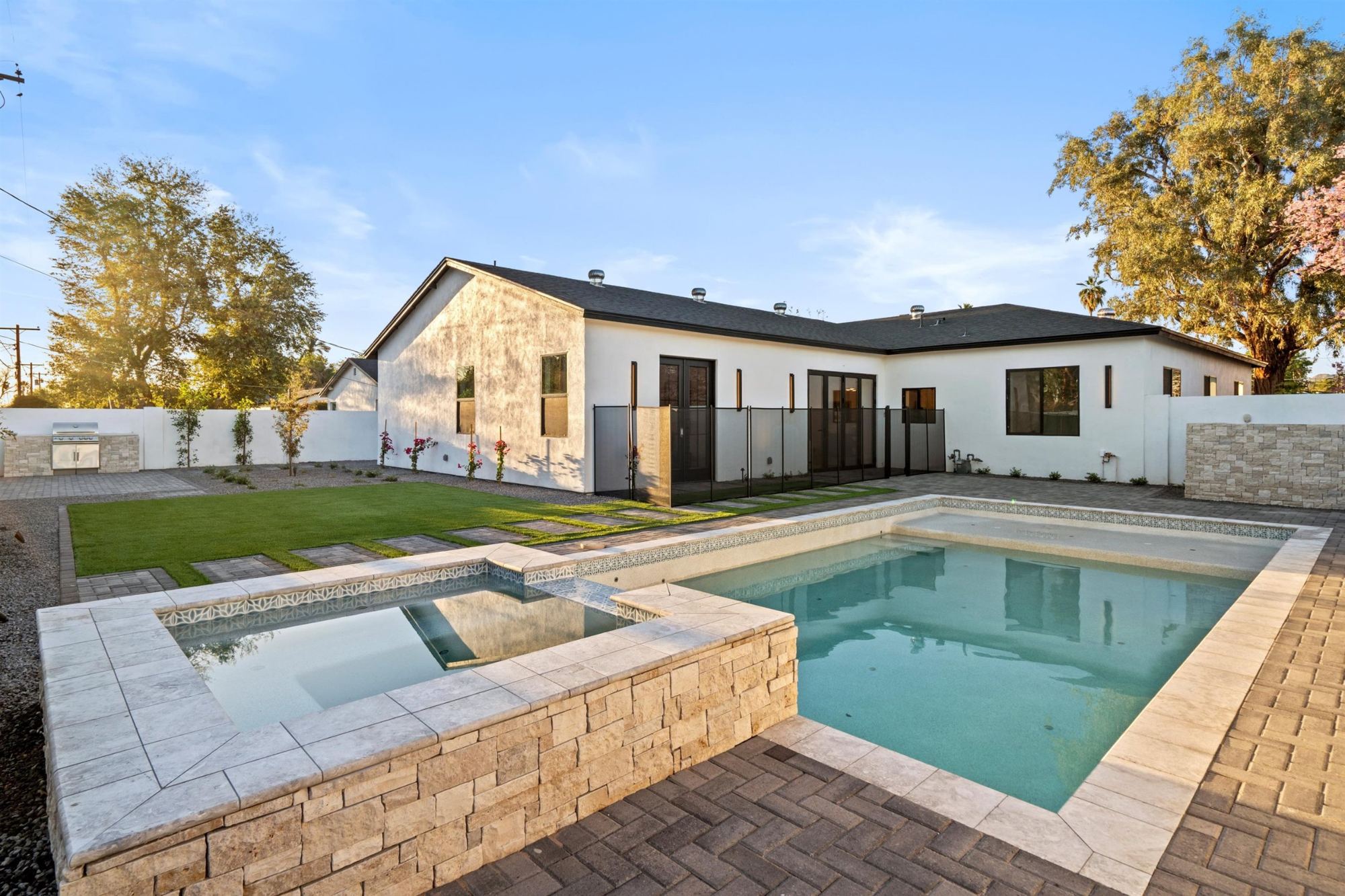 Backyard with pool, raised stone spa, turf and outdoor kitchen